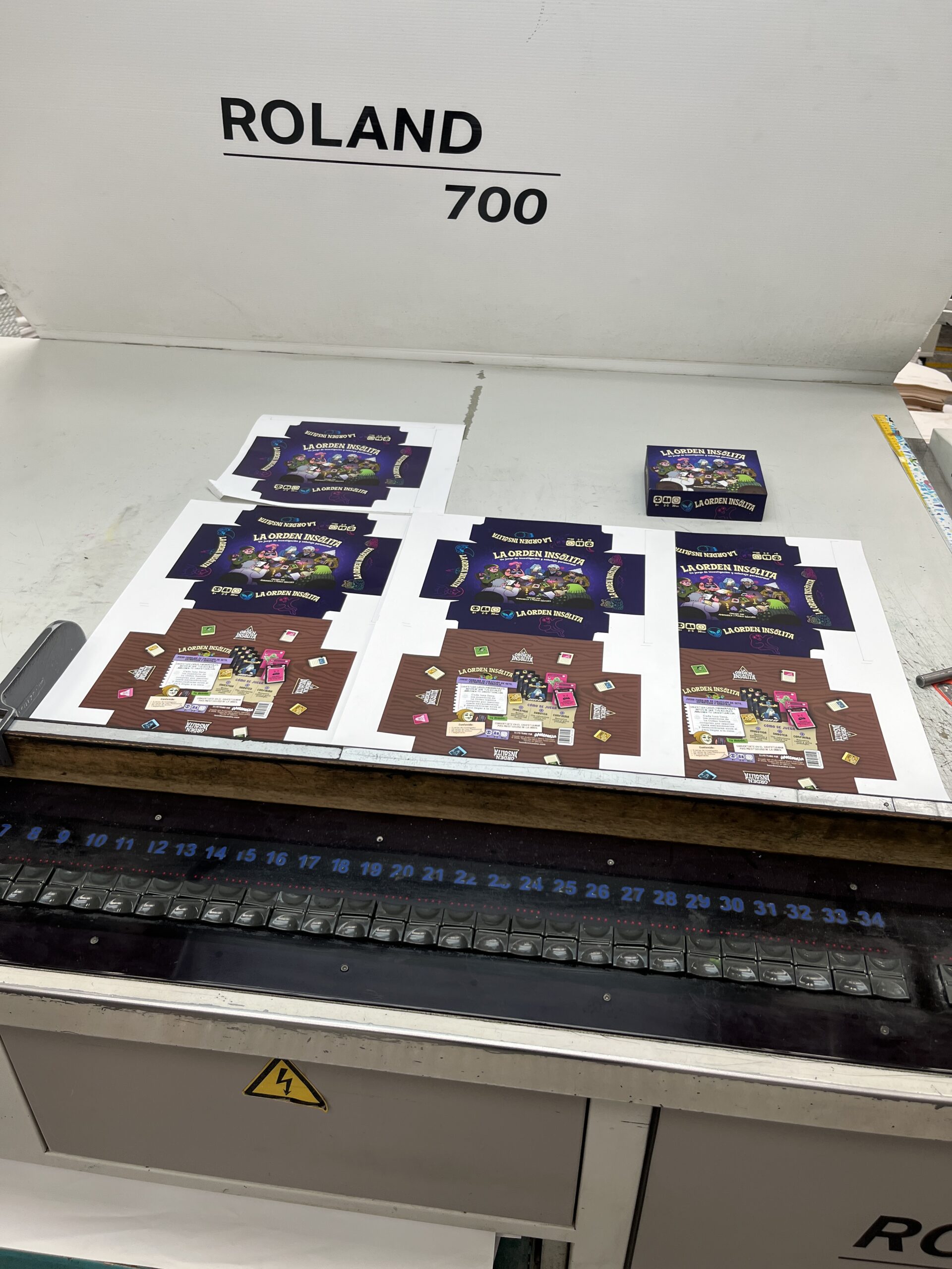 Pliegos de impresión con las primeras pruebas de color de la caja de La Orden Insólita en la prensa Roland 700 de Litografía Gil